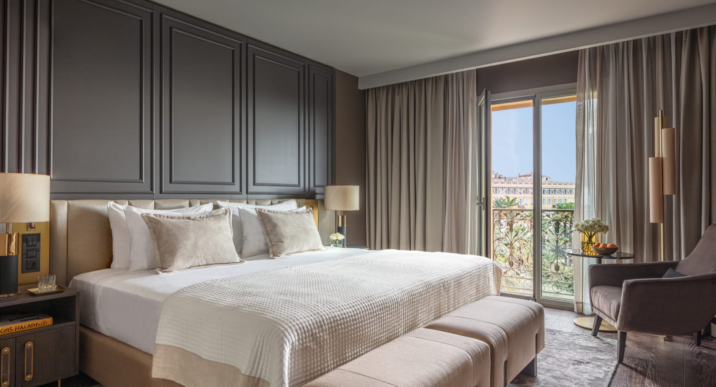 Elegant empty Nice hotel bedroom with refined neutral palette and classic French wall paneling