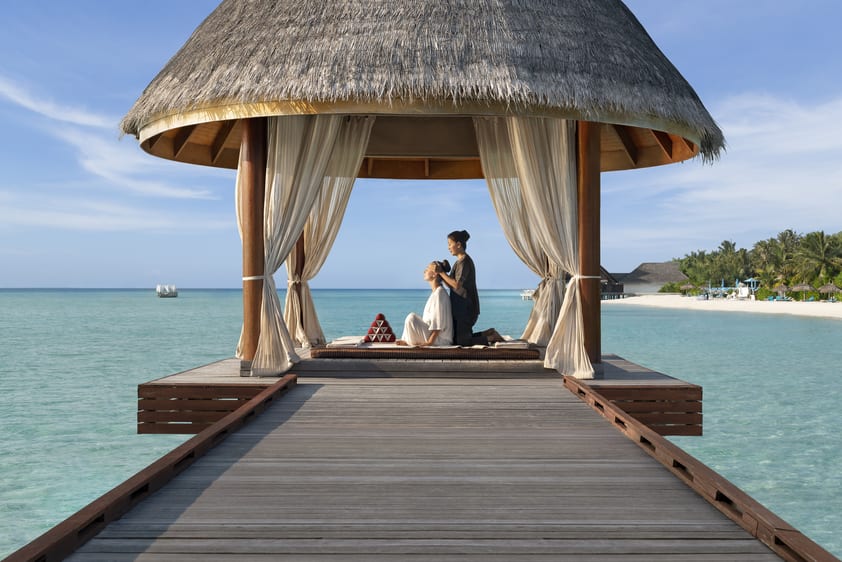 A woman and a masseuse during a massage treatment in front of the ocean.