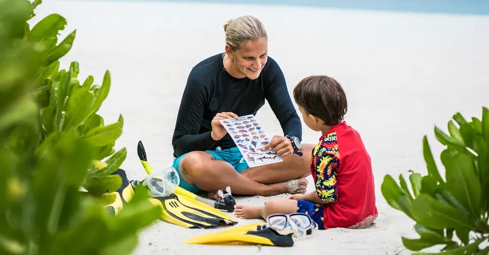 An instructor teaching a child about marine life on the beach.