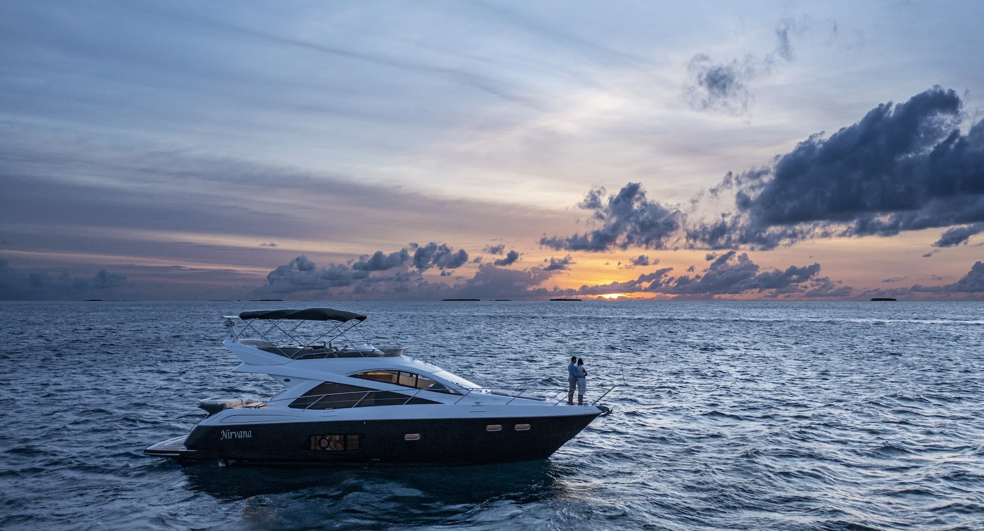 Sunset cruise at Anantara Dhigu Maldives Resort, featuring a traditional Maldivian dhoni sailing across a vibrant orange and pink sky