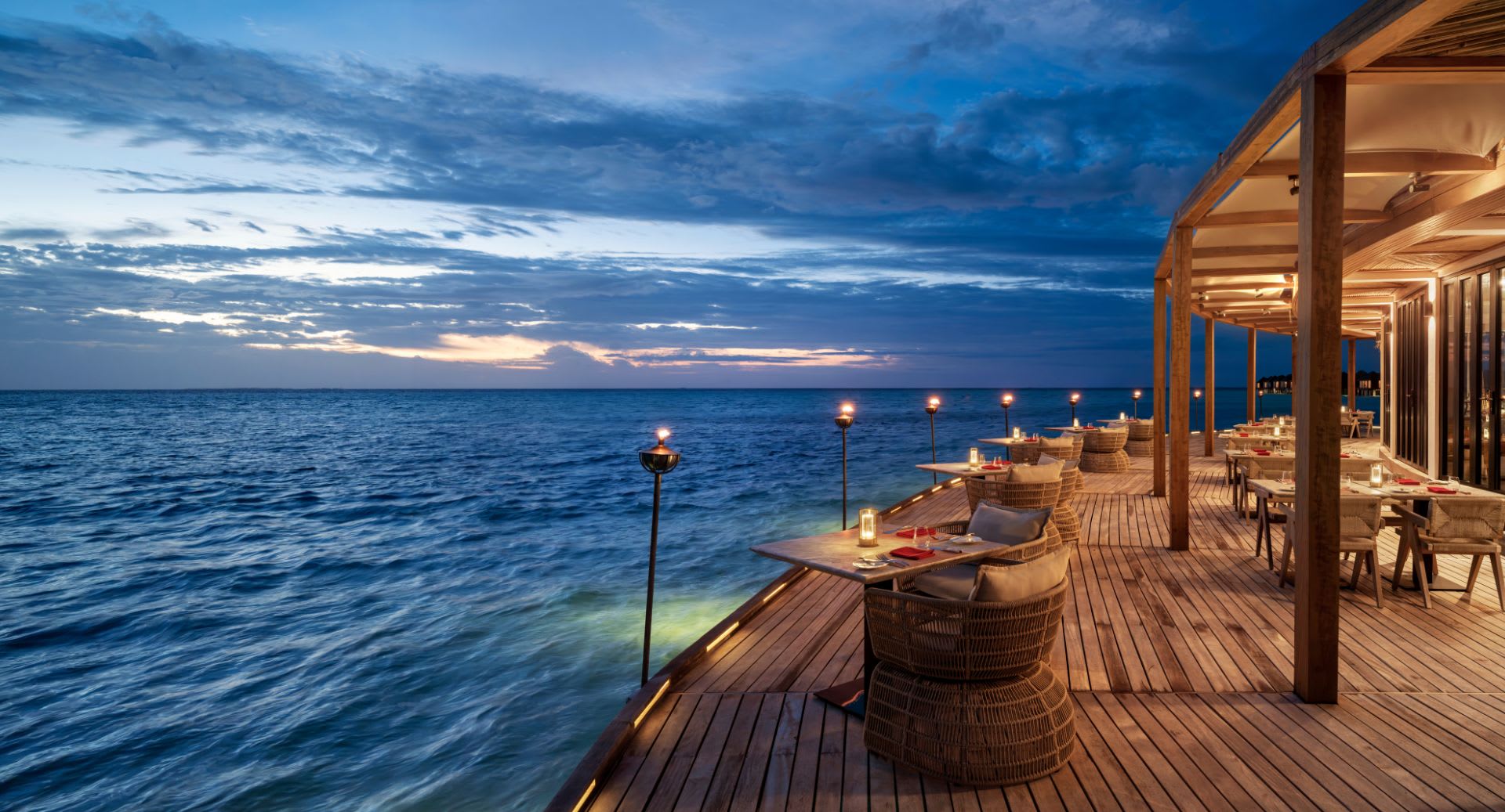 Evening deck view of the Sea Fire Salt restaurant at Anantara Dhigu Maldives Resort