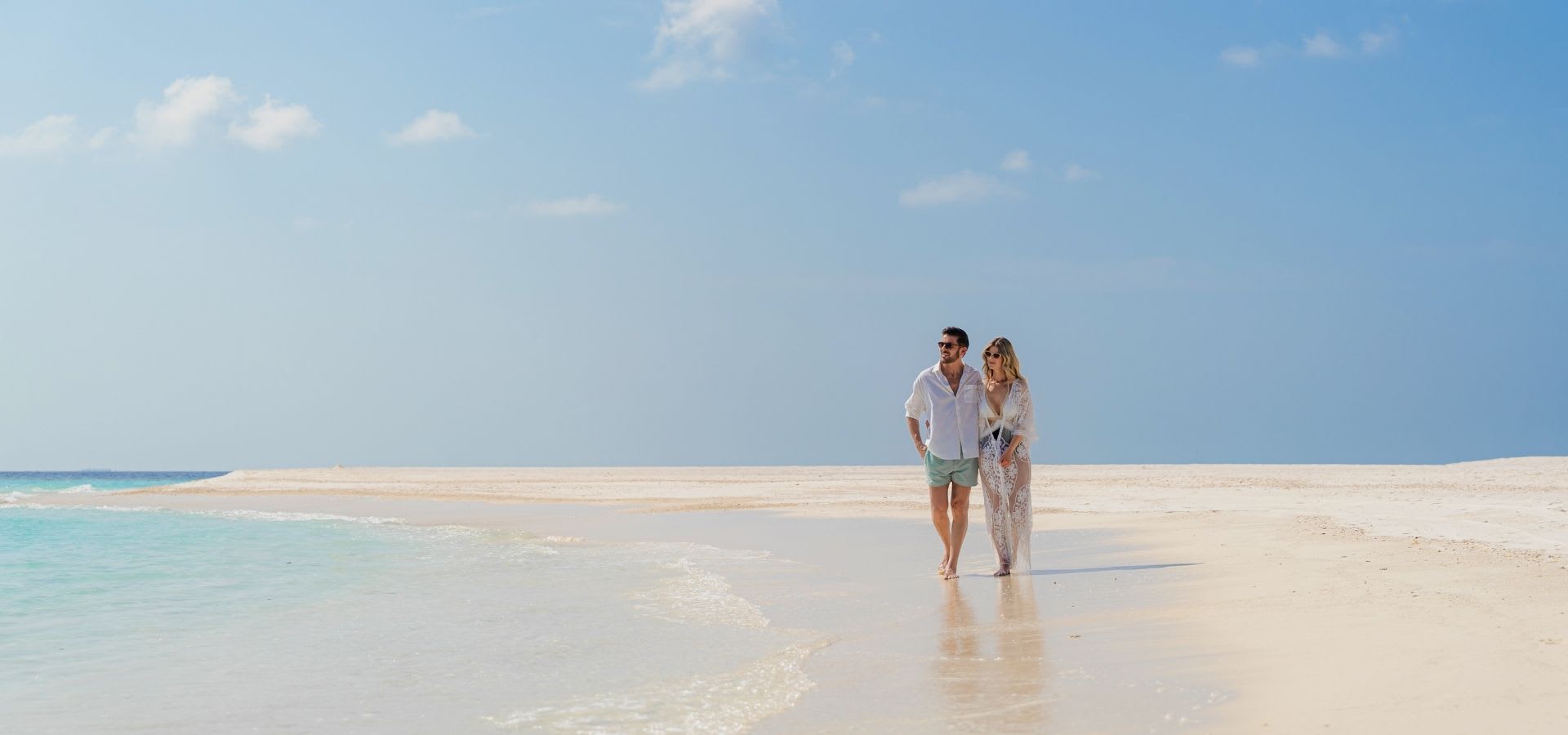 Couple is walking on the beach at Anantara Kihavah Maldives
