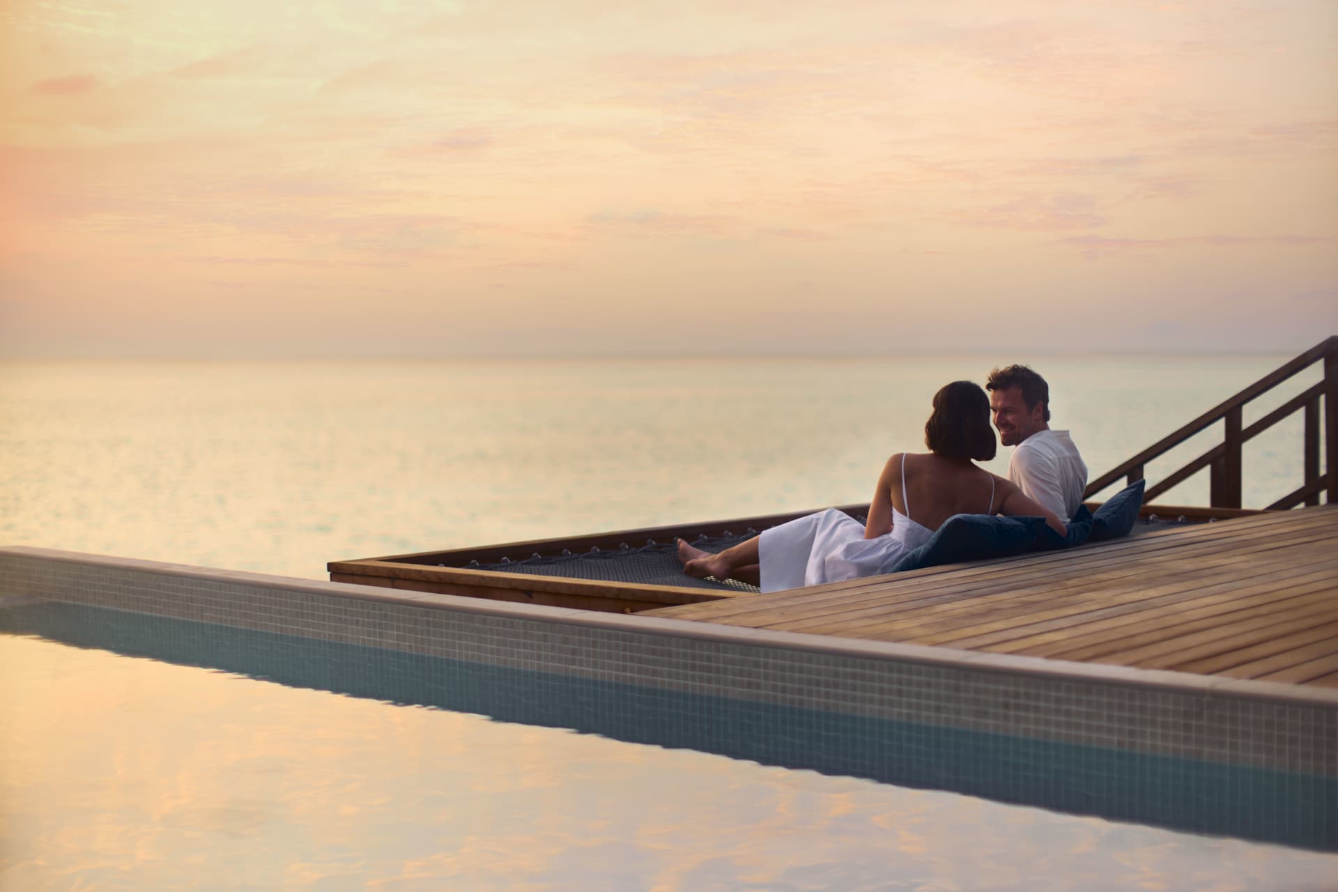 Couple enjoying the sunset by the pier at the adults-only resort, Anantara Veli Maldives Resort