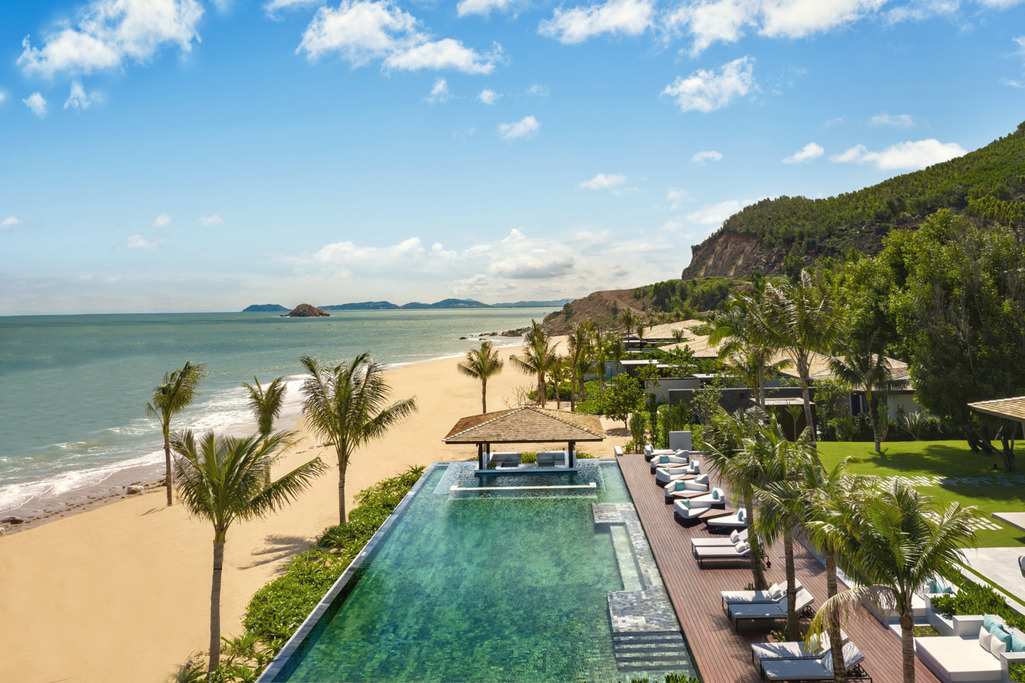 Anantara Quy Nhon Villas' swimming pool and beachfront with mountain at the back 