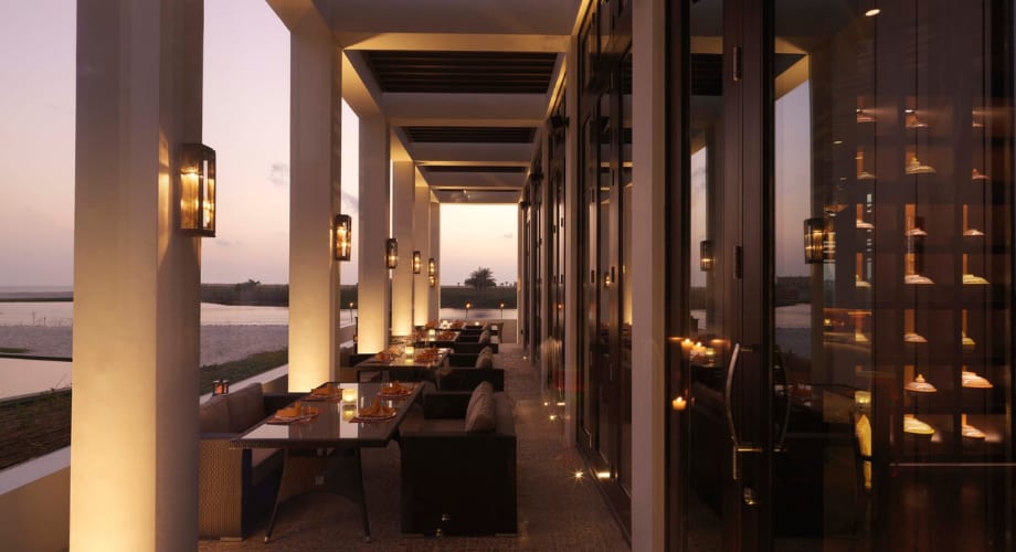 Terrace at Anantara Al Baleed Resort Salalah in the evening, tables set for dinner.
