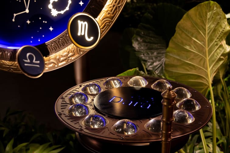 A decorative plate at Dara Cuisine Phuket, featuring a circular arrangement of clear spheres around the edge. The background includes zodiac symbols and a blue illuminated panel with the word "Dara".