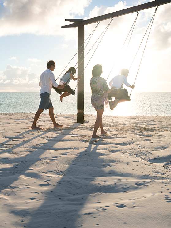 Family enjoying the swings on the beach at Anantara Dhigu Maldives Resort