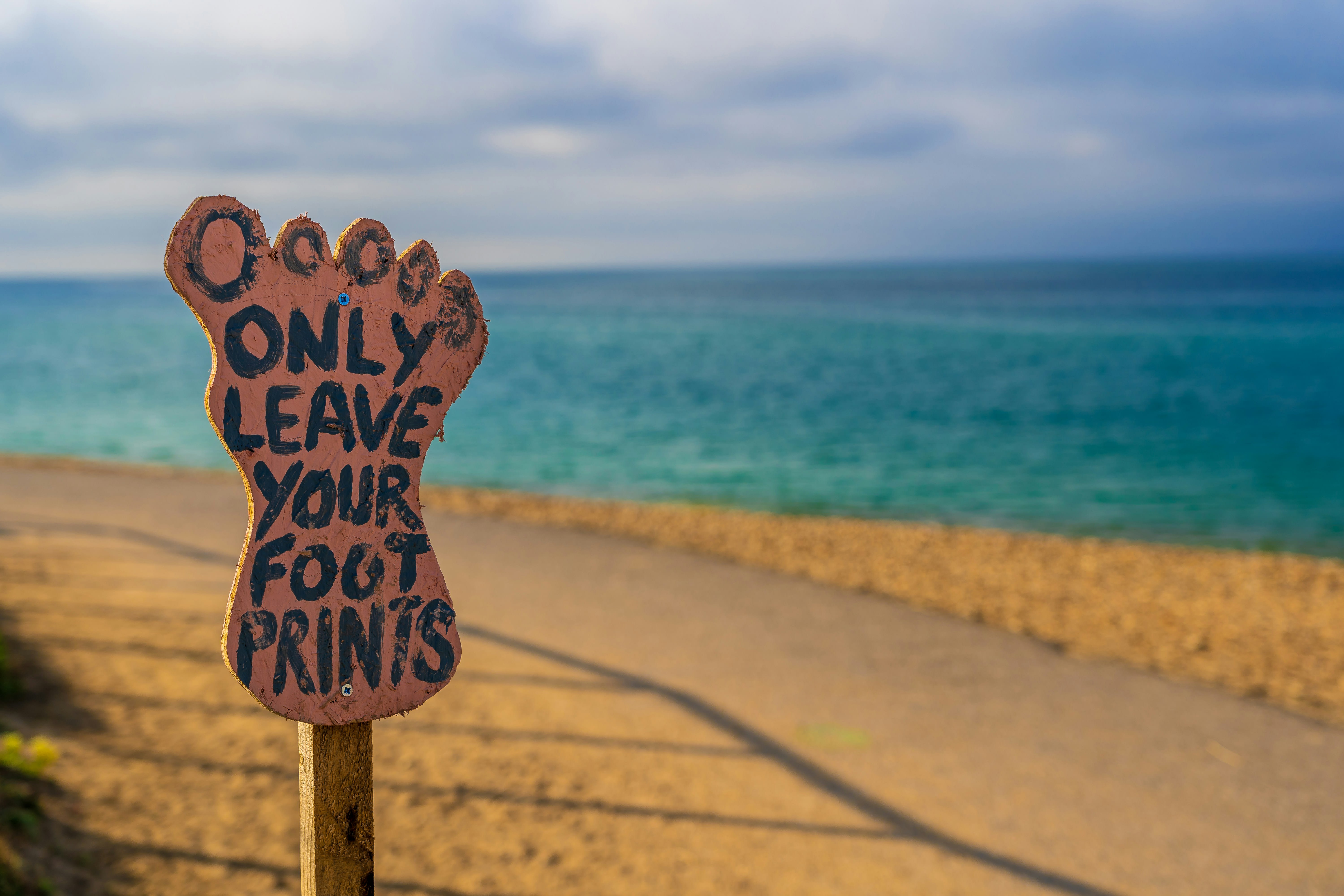 An "Only Leave Your Footprints" sign at the beach.