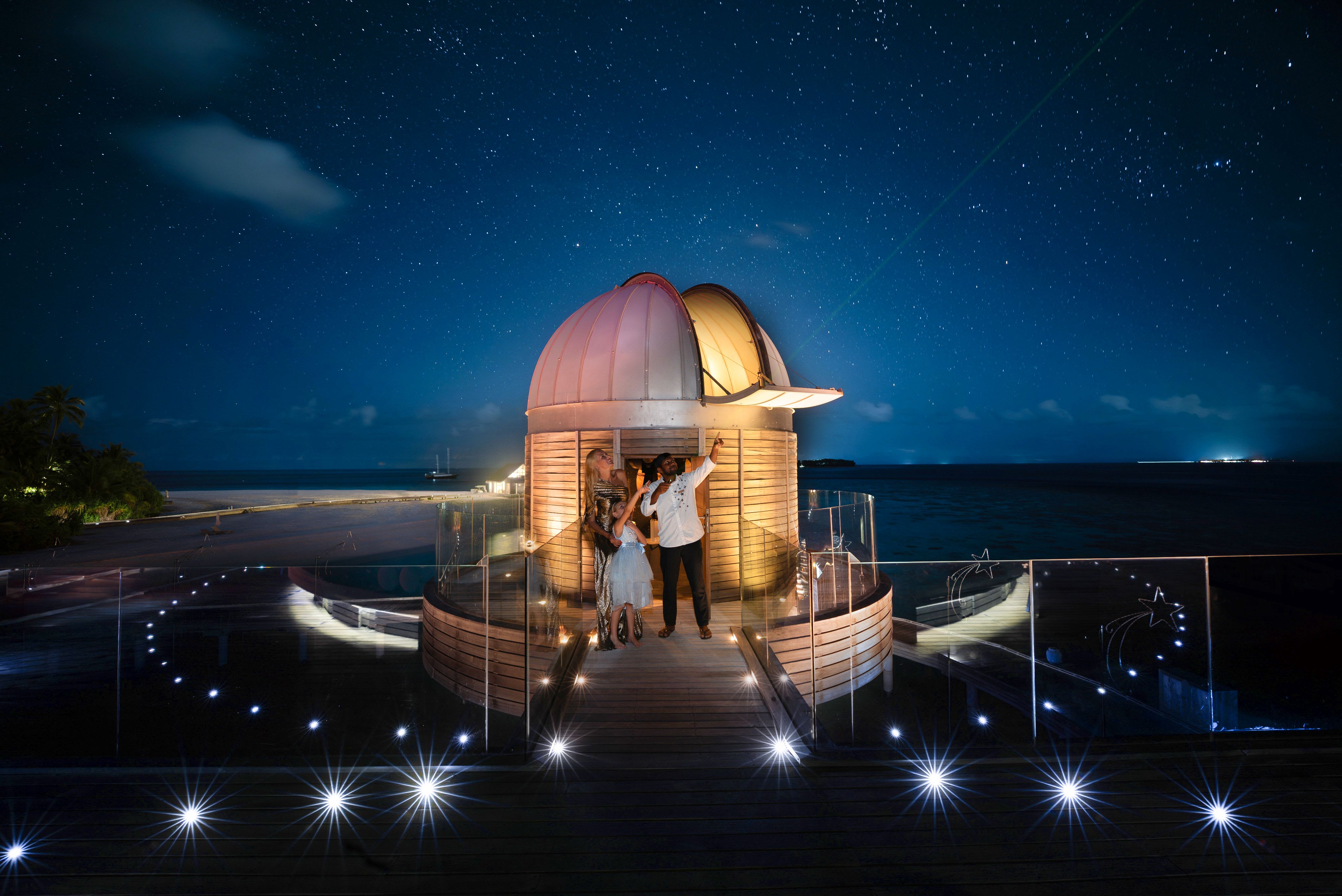 A SKY Guru guiding two guests on a stargazing experience.